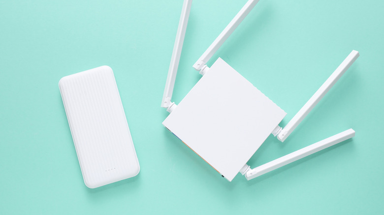 Unconnected white power bank and router on green background