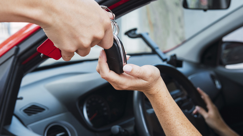 A hand giving car keys to a driver