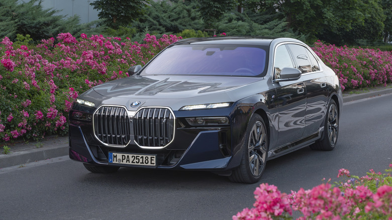 A two-tone BMW i7 driving on a road surrounded by flowers