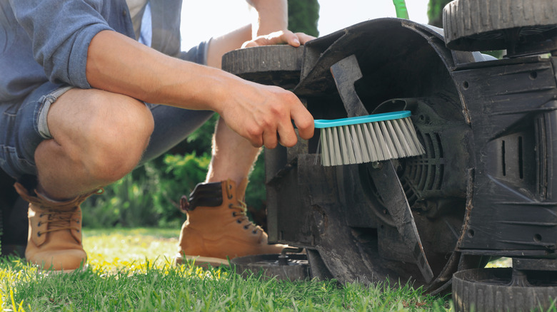 Man cleaning lawn mower blade