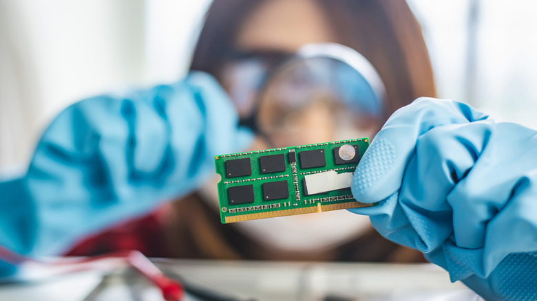 Technician examining computer RAM with magnifying glass
