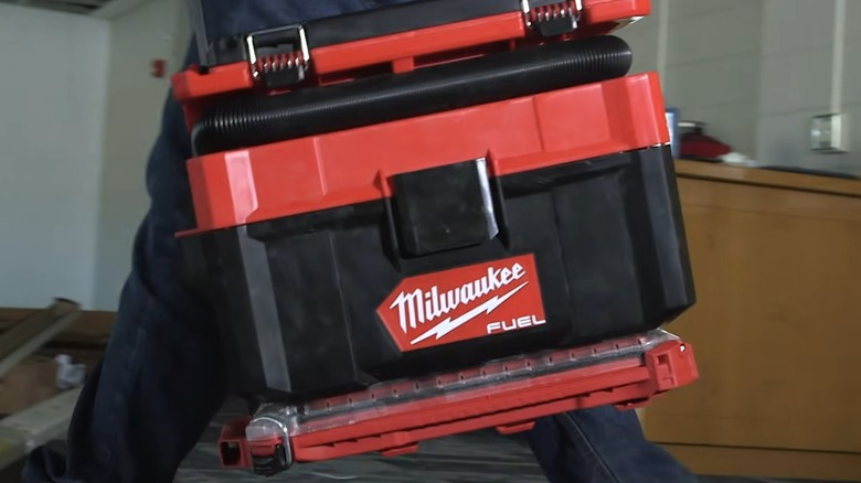 A person walking with a Milwaukee Packout container.