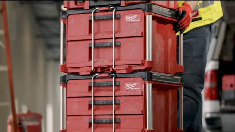 A person pushing a stack of Milwaukee Packout containers