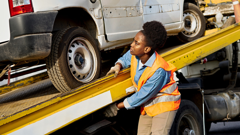 Woman loading car on to towing truck