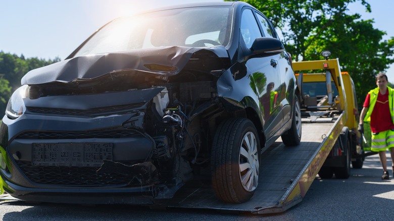 A damaged car being towed on a flat bed towing truck