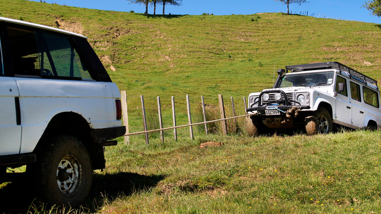 A car towing another car stuck in mud in a field