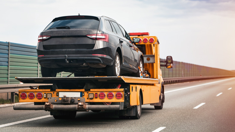 Flatbed truck carrying a car on the highway