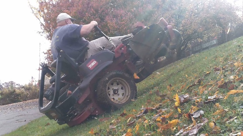 A Man Demonstrating The Danger Of Slopes Using A Zero Turn Mower Tipping Backwards