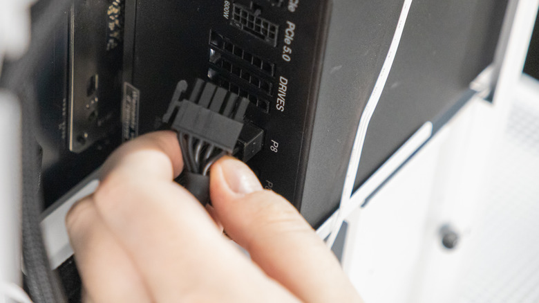 A technician is connecting a black power cable into the P8 port of a modular power supply unit inside a PC case. The close-up shows a step in building or upgrading a computer