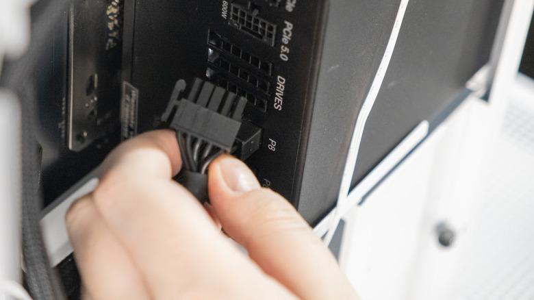 A technician is connecting a black power cable into the P8 port of a modular power supply unit inside a PC case. The close-up shows a step in building or upgrading a computer