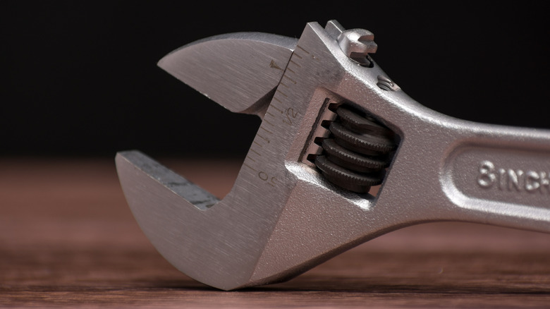 An adjustable wrench on a wooden table.