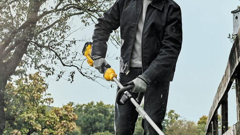 Man using DeWalt weed eater in backyard
