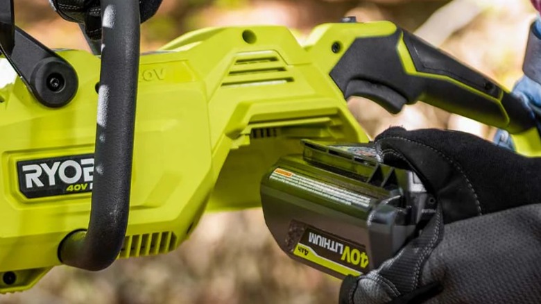 Hand plugs a 40V 4Ah battery pack into a Ryobi tool.