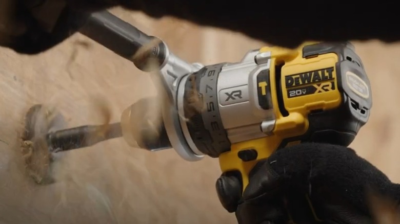 A person using a DeWalt hammer drill on wood surface