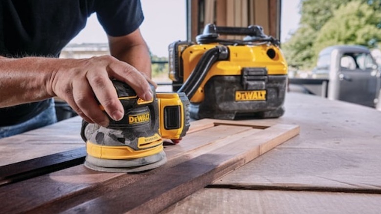 Person using DeWalt sander attached to shop vac