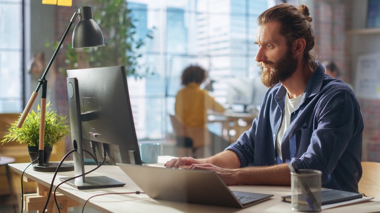 Man working on monitor with laptop
