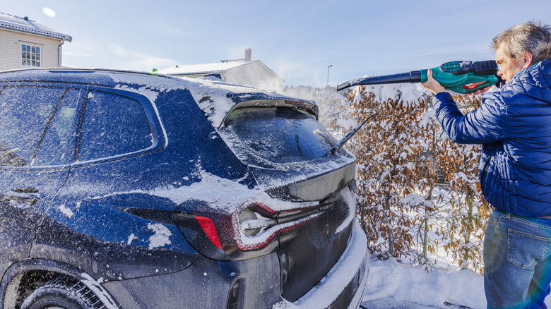 Person blowing snow off car with a leaf blower
