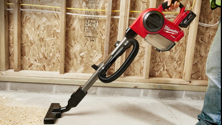 A person using a cordless Milwaukee vacuum.