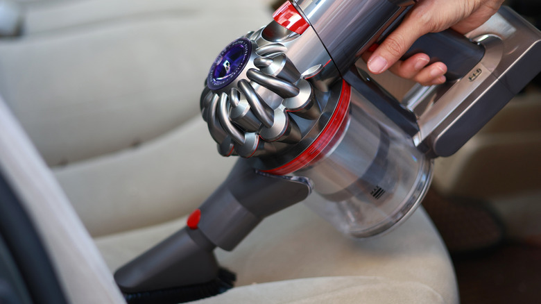 A person using a cordless Dyson vacuum.