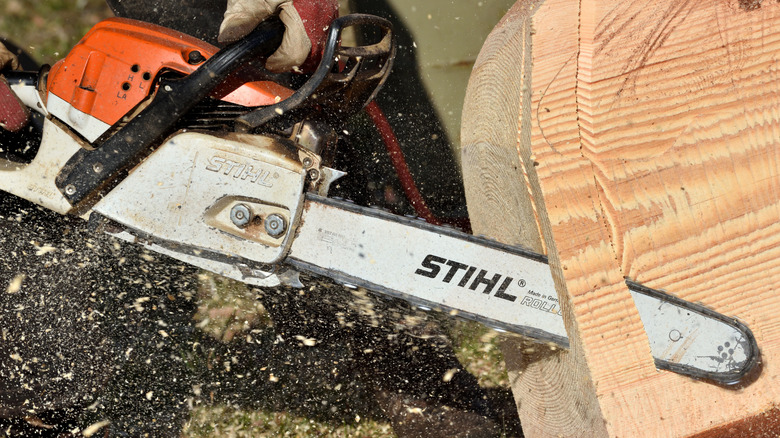 A person cutting wood with a Stihl chainsaw.