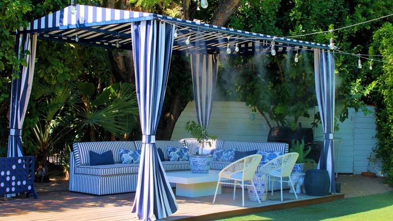 A cloth-topped gazebo over a patio with a water mister system in use to keep cool.