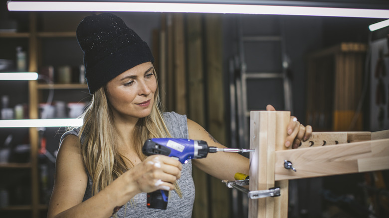 Woman using electric screwdriver as drill.