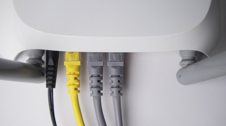 White router with a power cable and three Ethernet cables connected to it