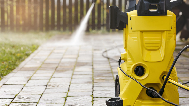 A pressure washer being used to clean outdoors.