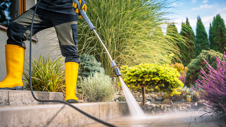 Person pressure washing concrete outdoors