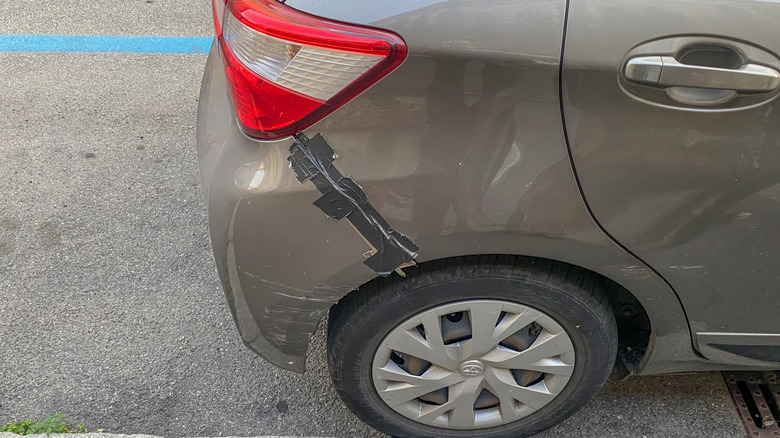 a gray hatchback with its rear bumper being held in place using black duct tape