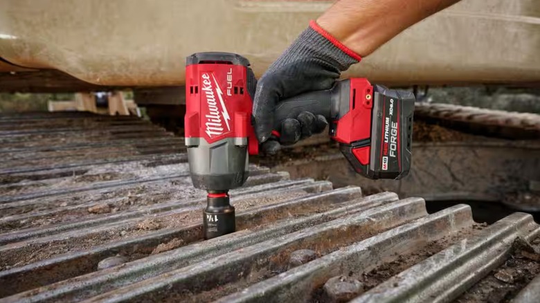 A person using a Milwaukee M18 Impact Wrench on a grate.