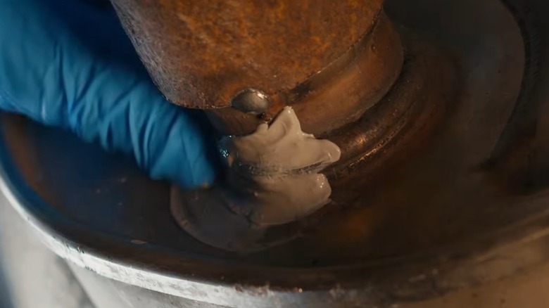 A person applying J-B Weld to exhaust components.