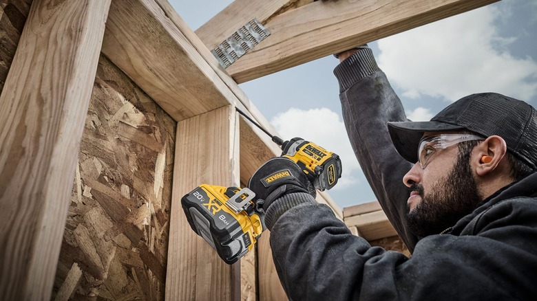 A worker using a DeWalt 20V Max impact driver.