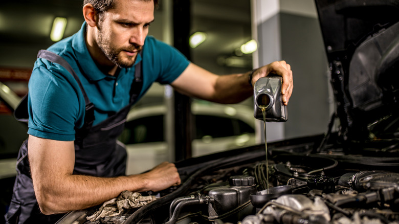 A mechanic changing motor oil in a car