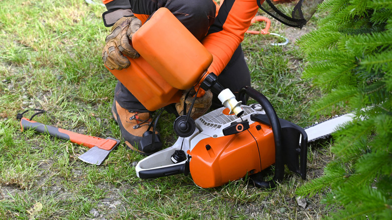 Man refueling chainsaw on the ground