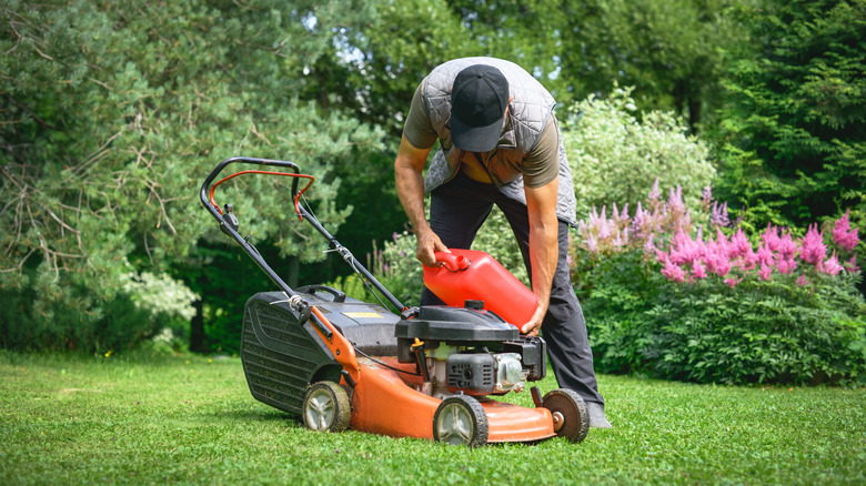 A man refueling a walk-behind mower