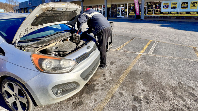 Car battery being changed outside an Advance storefront