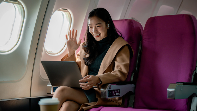 A woman using a laptop while on an airplane