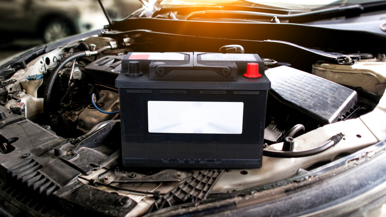 A car battery resting on the front of a car.