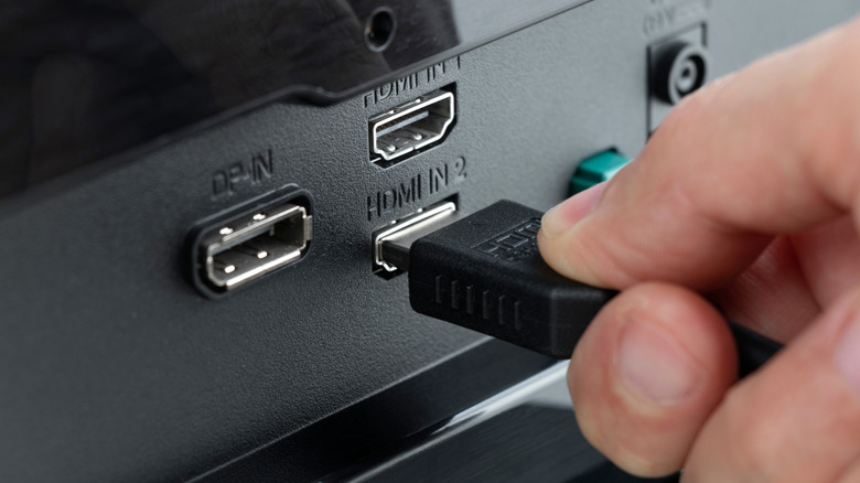 Someone plugging an HDMI cable into a TV's HDMI 2 port.