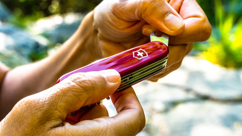 Person unfolding Swiss Army Knife bottle opener tool