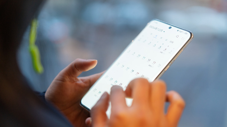A person checking a calendar on his Android smartphone.