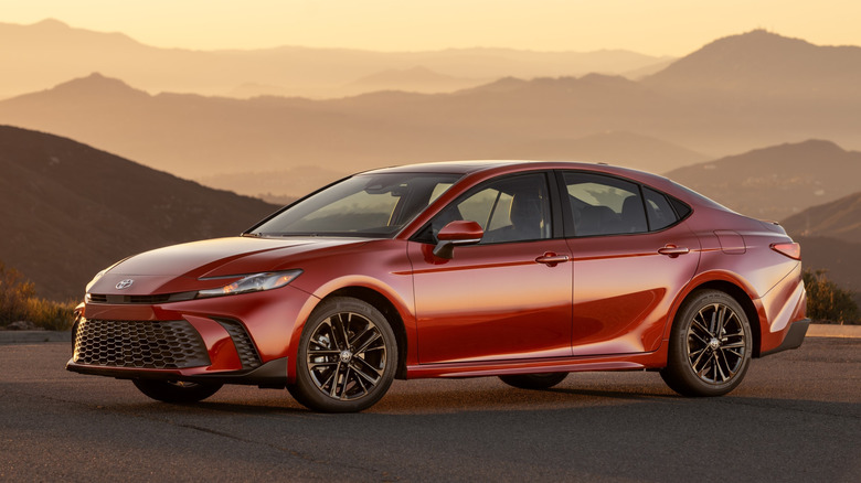 Front 3/4 view of red Toyota Camry SE parked in mountains at sunset.