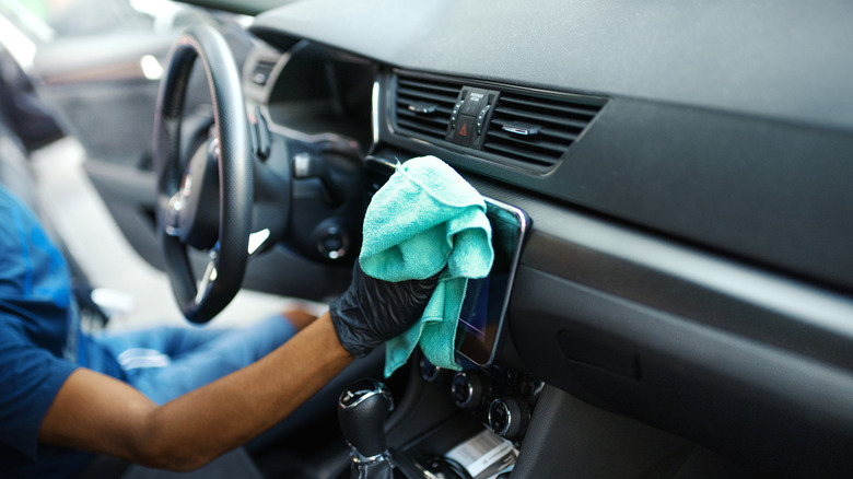 Man detailing interior of vehicle with a microfiber cloth