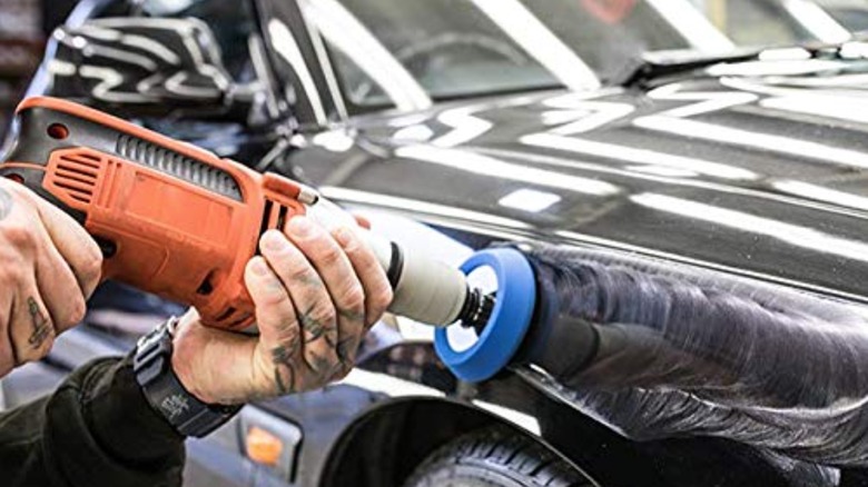 Person using buffer to remove polis from a car
