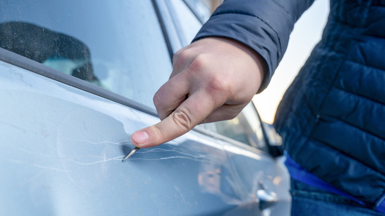 Person scratching a car with a key