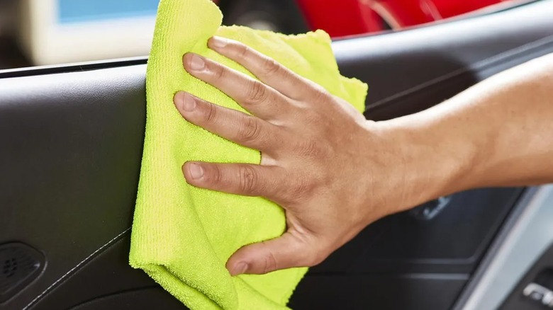 A person using a Grant's microfiber cloth on a car door.