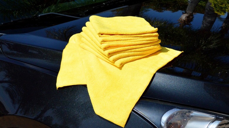 Several Kirkland microfiber towels on the hood of a car.