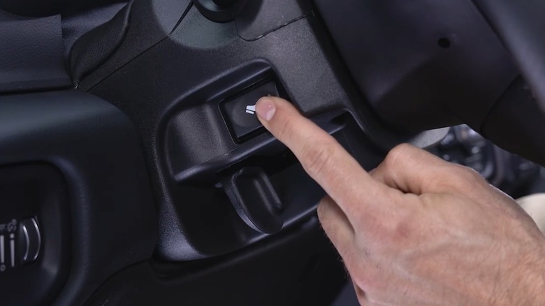 A driver pushing the power-adjustable pedal button on a Ram truck