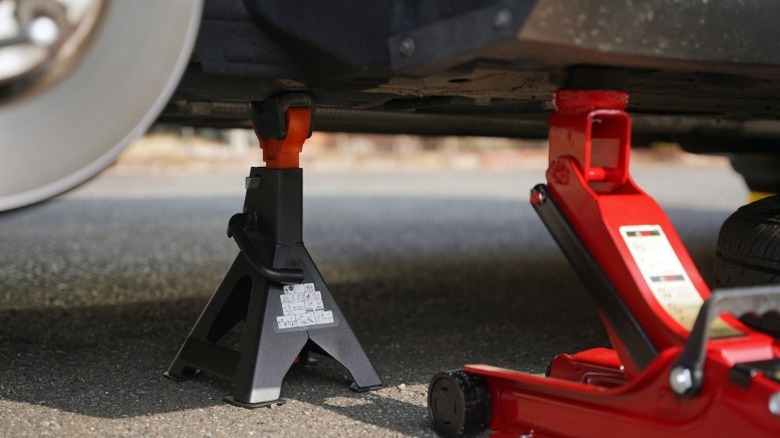 An image of a floor jack and a jack stands supporting a vehicle